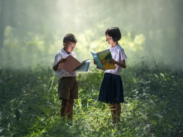 a young boy and a young girl standing, holding, and reading books in a forest