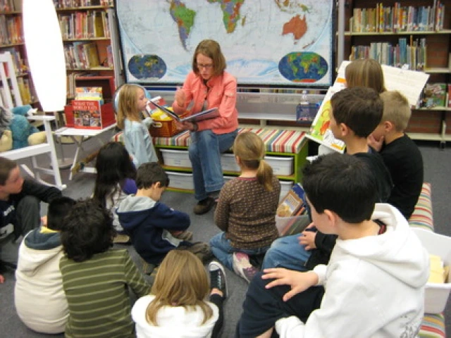 female teacher reading books to kids in a library