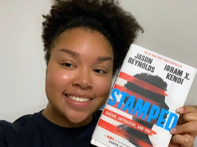 a black lady smiling holding a book titled stamped closed to her face