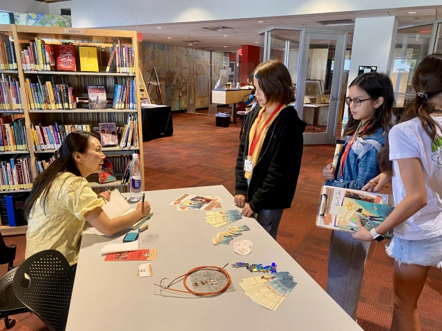 middle schoolers wait for a woman to sign their books