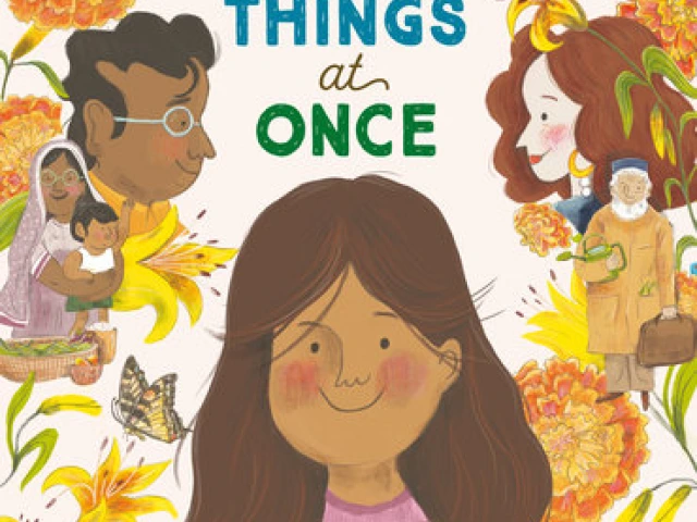 A smiling girl holds a camera. Behind her are flowers and members of her family from her mother and father's sides.