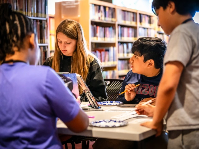 four middle schoolers focused on an activity around a table