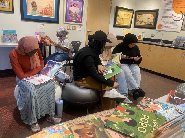 A group of students seated on benches and at a table, each reading their own books.
