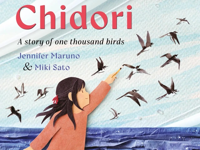 A young girl paints ink birds that fly over an ocean made of blue paper.