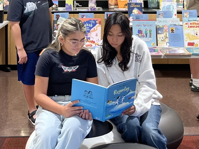 two middle school readers sitting on pods to share a picturebook.