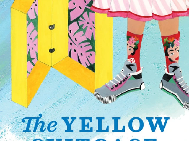 An open yellow suitcase next to the legs of a young girl