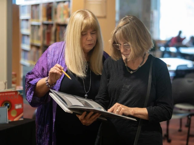 Kathy Short and Gudrun Godare read a visual narrative at exhibit reception