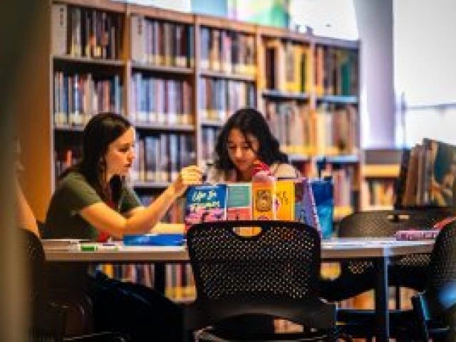 Two reading ambassadors sit at a table reading books.