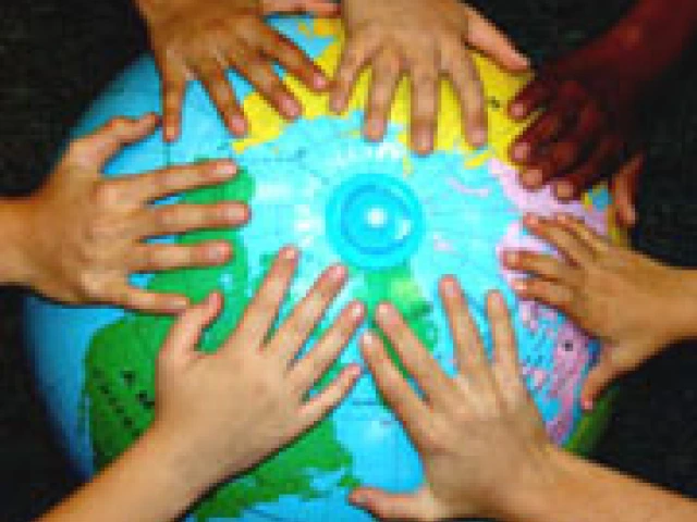 The hands of children with varying skin tones on the northern hemisphere of a globe