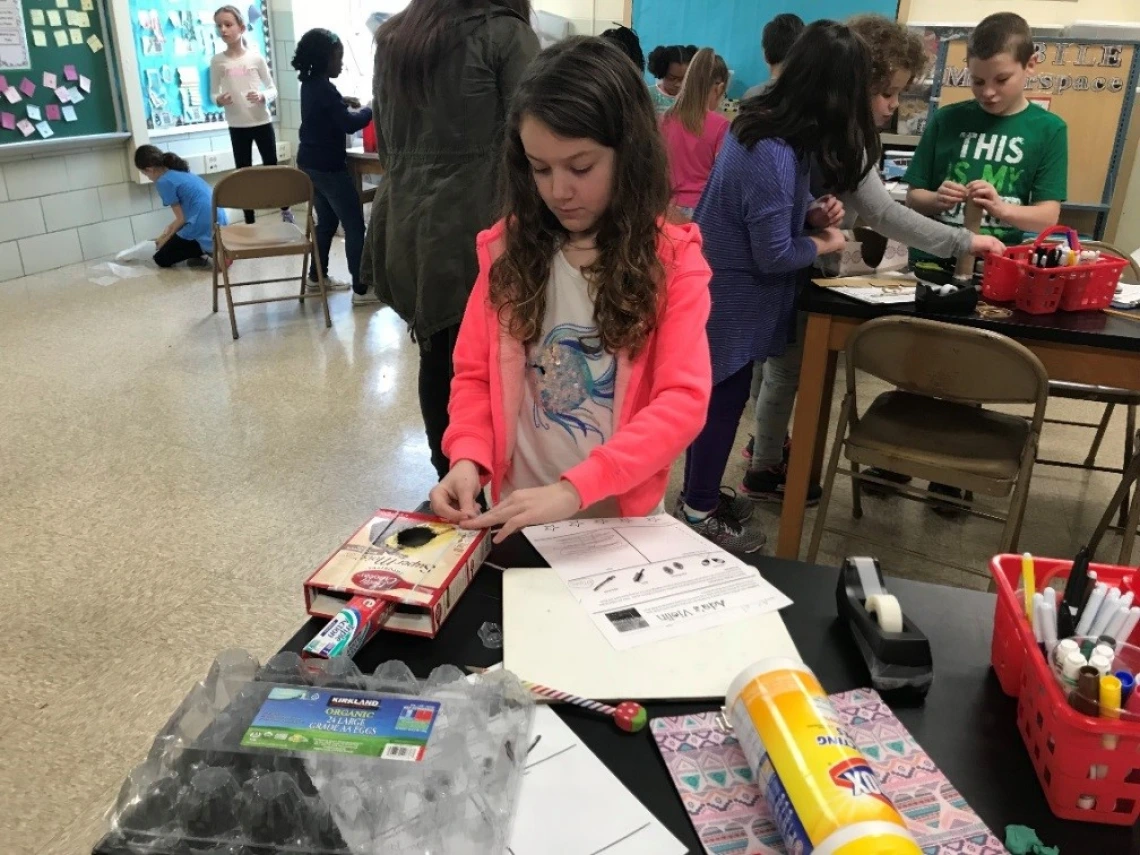 Alex selected some cardboard boxes and rubber bands to create her string instrument