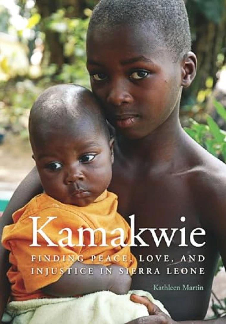 In an outside setting, a child is holding a baby in his arms