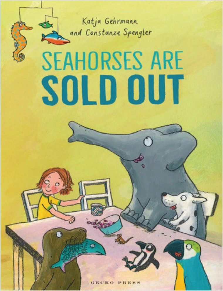 A boy sits at the dinner table with a seal, a fish, two birds, a mouse, a dog and an elephant. 