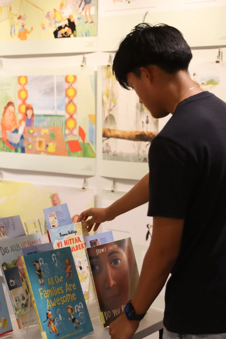 Mexican American college student looks at a display of picture books in English and German