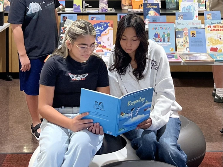 two middle school readers sitting on pods to share a picturebook.