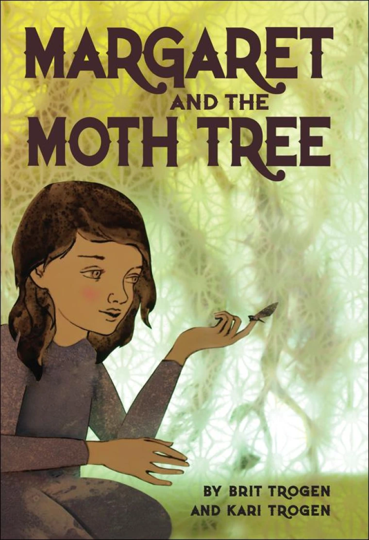 A girl is holding a moth on her finger