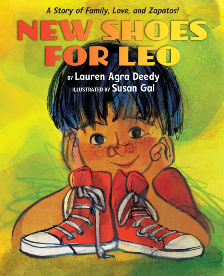 A young boy smiles with a pair of new red shoes in front of him.