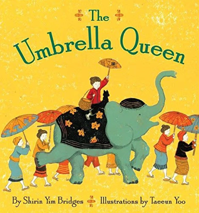 A woman rides an elephant while holding an umbrella. Other women with umbrellas walk beside the elephant.
