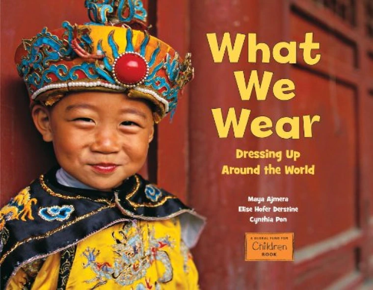 A young boy in yellow traditional Chinese clothes smiles at the camera.