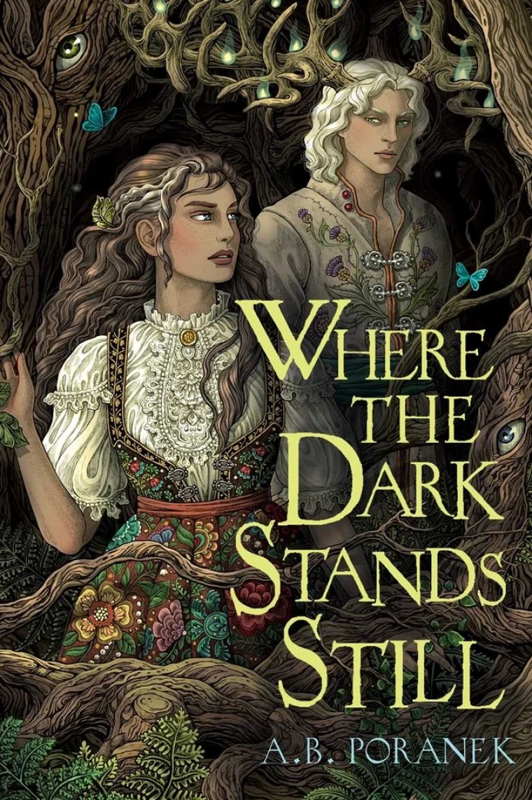A teenage girl stands in a forest with a blonde man behind her.