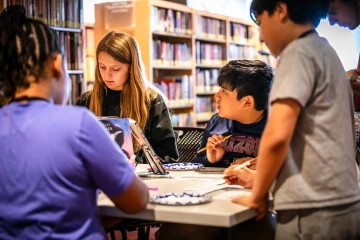 four middle schoolers focused on an activity around a table