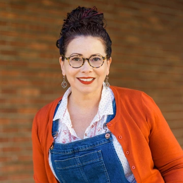 Picture of Donna Barba Higuera, a woman with curly brown hair up in a bun and glasses. 