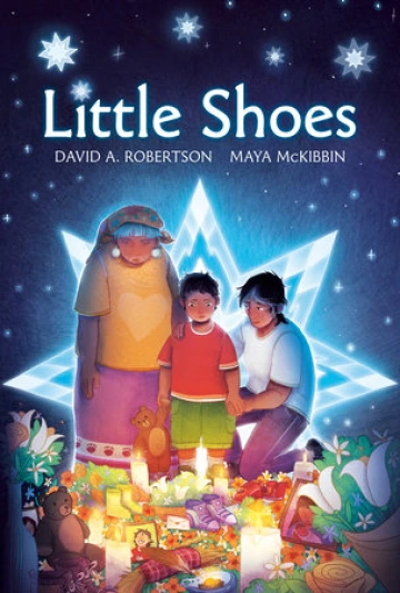 A young Indigenous boy looks down at a memories of candles, toys, flowers, and shoes with his mother and grandmother.