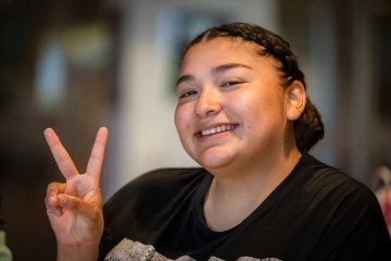 Smiling teen girl holds up the peace sign 