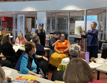 A woman presents a picturebook to a crowd of people