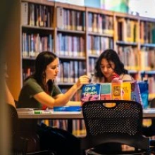 Two reading ambassadors sit at a table reading books.