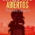 Cover of Con los ojos abiertos depicting a girl with a ponytail holding a book to her chest. Everything is shaded in red, with the girl being the darkest red and the background a lighter red.