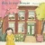 Cover of This Is Our House depicting a young Korean girl in a yellow dress in front of a brick house.