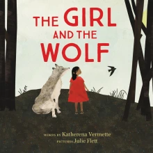 A young girl in a red dress is next to a large gray wolf.