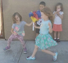 two girls running while they exchange a batton capped with colorful tissue paper