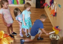 child kneels in pretend to light a flame with his baton torch topped with colorful tissue paper