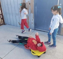 child laying on three colorful scooters