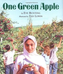 Cover of One Green Apple depicting a yong girl in a light colored hijab holding an apple with an apple orchard in the background, where other children pick apples.