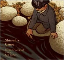 A young Native American boy holds a small wooden canoe