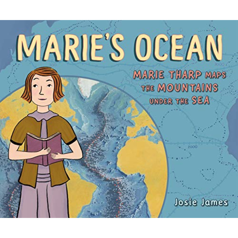 A white woman with short brown hair holds a book and stands in front of a map of the Mariana Trench.