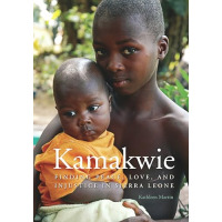 In an outside setting, a child is holding a baby in his arms