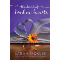 A book is laid flat with its pages folded into a heart and in between the pages pokes out a flower