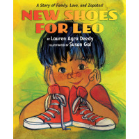 A young boy smiles with a pair of new red shoes in front of him.