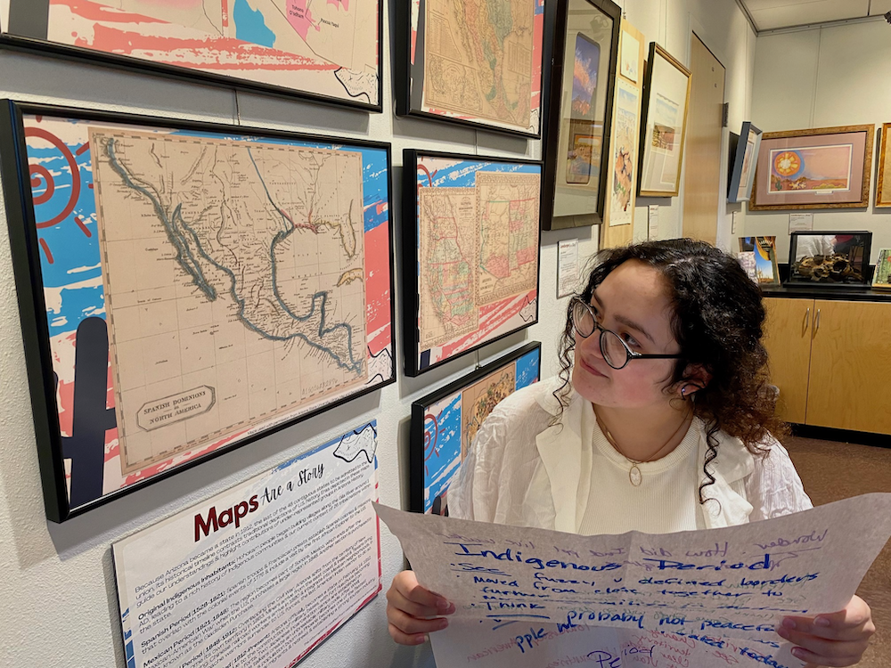 Young woman compares maps of Arizona to a hand-written chart