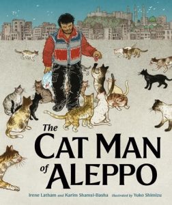 A man feeds many cats with the city behind.