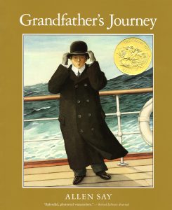 Grandfather stands on the deck of a ship holding his hat in the wind.