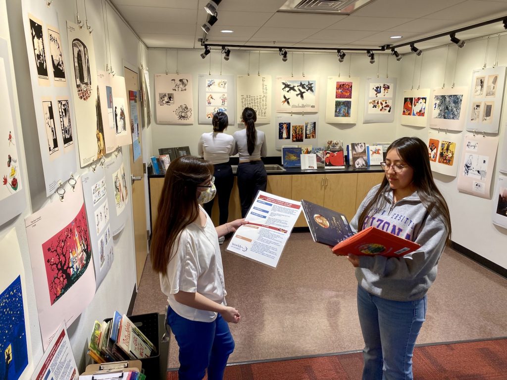 two women compare different stories of Little Red Ridinghood, two other young women look at illustrations in the background