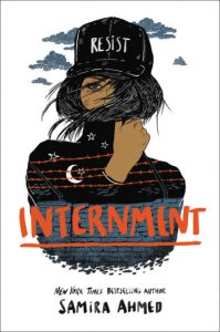 Cover for Internment shows a teen girl with her face obscured wearing a baseball cap with RESIST printed on it, overlaying her shirt is an image of a wall topped with barbed wire