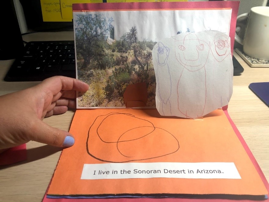 Zoey's drawing of herself in the foreground of the page, a bolder in the background, and a snake on the ground.