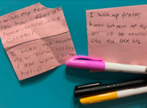 Pink post it notes on a blue background with three pens beneath them.