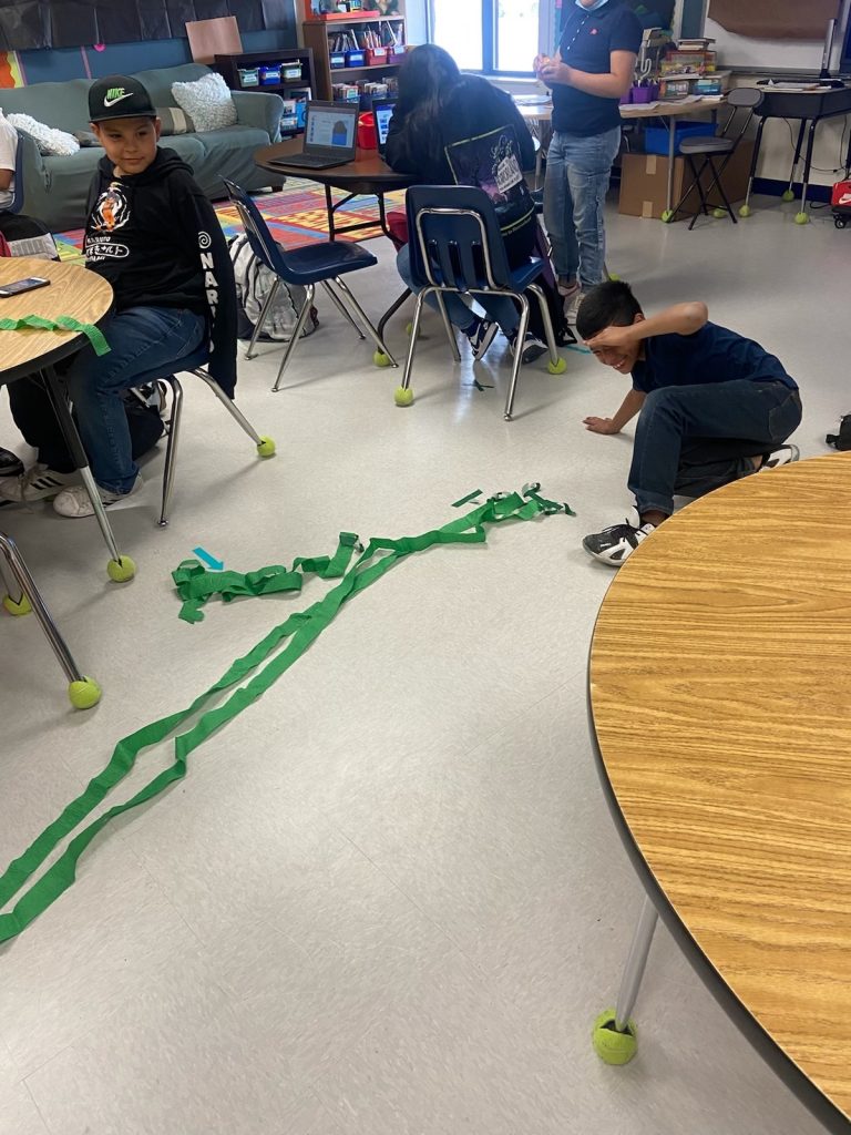 child lays out green streamers on the floor to represent a beanstalk