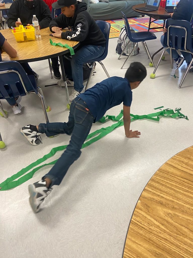 child pretends to climb the beanstalk he created on the floor with green streamers